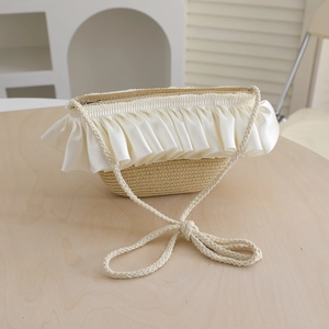 Detail of handwoven straw bag with elegant cream satin ruffled edge and long shoulder strap