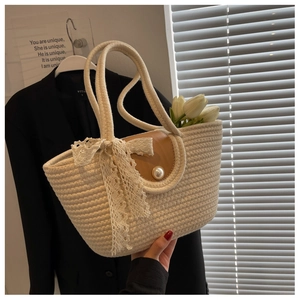 Detail of straw woven tote with brown leather flap, pearl clasp and lace bow accent