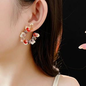 Detail of luxury U-shaped zircon earrings with multicolor gemstones on a female model