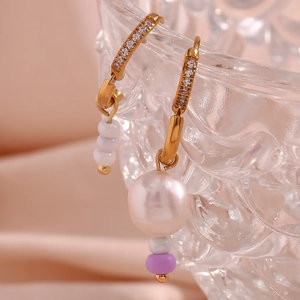 Makro-Detail von goldenen Perlenohrringen mit lila Perlen auf einem Glasrand