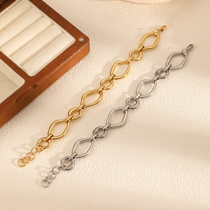 Detail of geometric open-link chain bracelets in gold and silver over a wooden box