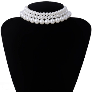 Macro view of triple-layered faux pearl choker necklace on a black velvet mannequin