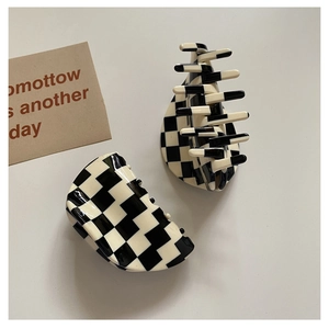Close-up of two large black and white checkerboard hair claws on a clean background