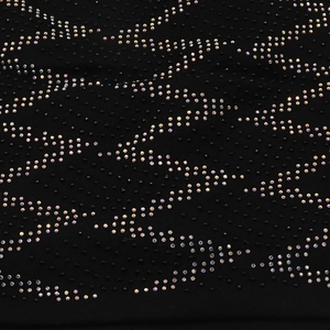 Macro shot of colorful rhinestones and black beads on cotton fabric with wave pattern