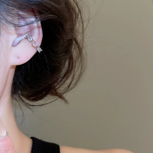 Silver ear bone cuff with four sparkling white zircons worn on model's ear side view