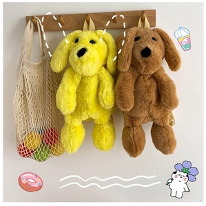 Detail of cute yellow and brown fluffy dog plush backpacks on a wooden hook hanger