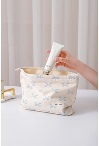Detail of cream cotton cosmetic bag with blue bow pattern and hand cream insertion