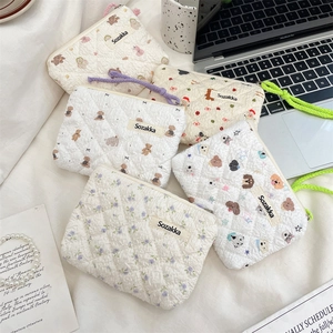 Flat lay of small floral quilted cotton pouches with bear and dog patterns for daily use