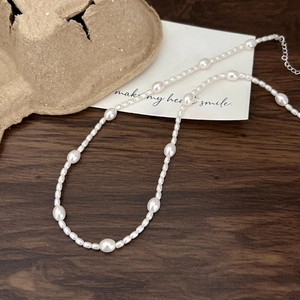 Close-up of irregular white pearls on a minimalist necklace with a metal extender chain