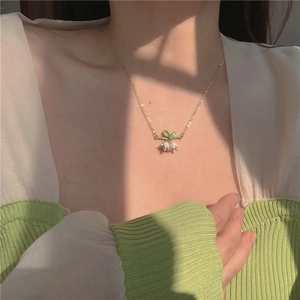 Elegant lily of the valley necklace with white flower petals and green leaves on gold chain