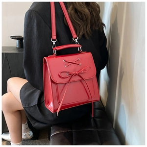 Detail view of red PU leather backpack featuring bow-knot design and shiny metallic eyelets