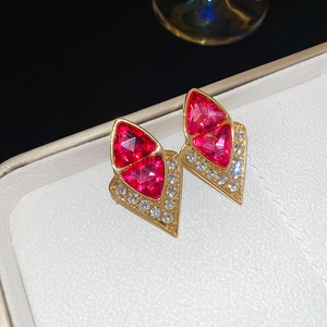 Close-up of vintage gold geometric earrings with red gemstones and white crystals in a box
