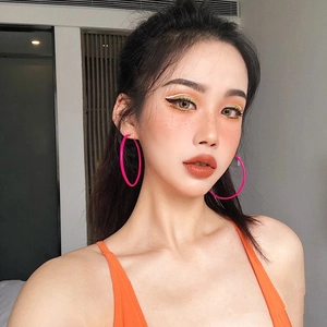 Gros plan d'un mannequin portant de grandes créoles roses mates avec finition gomme