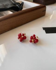 Detail of red berry stud earrings with gold plating and sparkling zircon accents