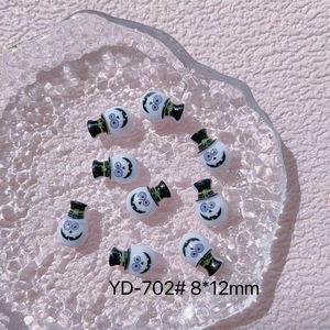 Macro view of tiny white resin ghosts with black hats and purple eyes for Halloween nail art