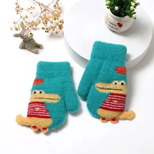 Detail of blue knitted toddler mittens with cute cartoon crocodile pattern and neck string