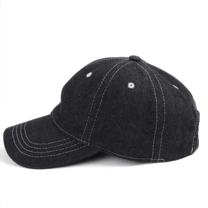Detail view of black washed denim baseball cap featuring white contrast stitching and soft top