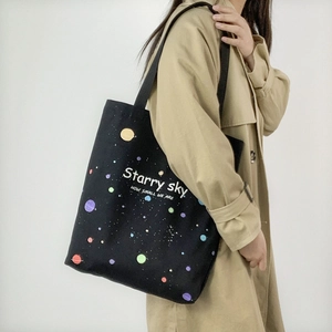Détail du sac fourre-tout en toile noire avec imprimé ciel étoilé et doubles poignées
