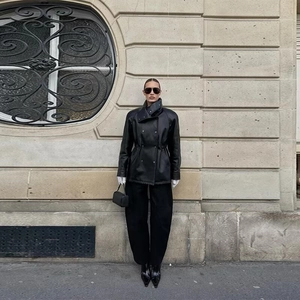 Détail d'une veste en similicuir noir avec col montant et cordon de serrage à la taille