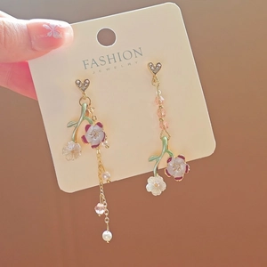Close-up of asymmetric flower tassel earrings with pearls and crystals on a card