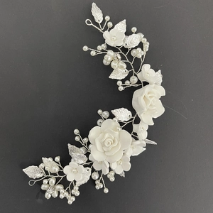 Close-up of white clay flowers and silver alloy leaves on a bridal hairpiece
