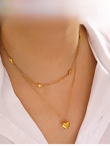 Détail du collier double rang doré avec pendentifs en cœur sur un mannequin femme
