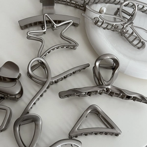 Detail of silver metal bow hair claws with pearl accents on marble surface
