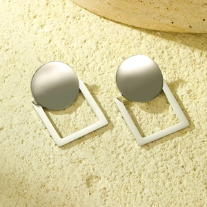 Dettaglio di orecchini geometrici in argento con forme tonde e quadrate su base pietra