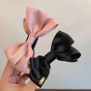 Elegant large satin bow hair claws in pink and black colors with metal logo plates