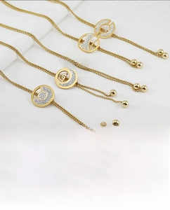 Detail showing five 18K gold-plated adjustable necklaces with diamond-encrusted charms