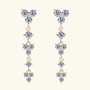 Detailed close-up of gold dangling tassel earrings with sparkling crystals and petal motifs