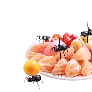 Creative black ant-shaped plastic fruit picks displayed on fresh sliced fruits in white background