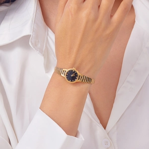 Detail of vintage gold women's watch with black round dial on a striped metal band
