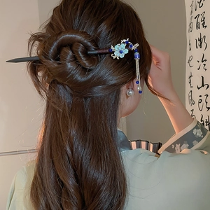 Detail of elegant Chinese style hair pin with blue floral motifs and bead tassels on a bun