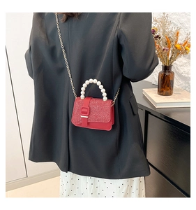 Detail of red glitter mini crossbody bag with faux pearl handle and gold chain strap