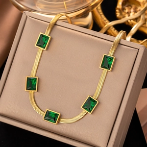 Close-up of a vintage gold snake chain necklace with five rectangular green gemstones