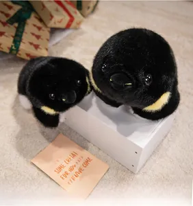 Détail de deux peluches de bébés manchots avec fourrure douce et détails jaunes au cou