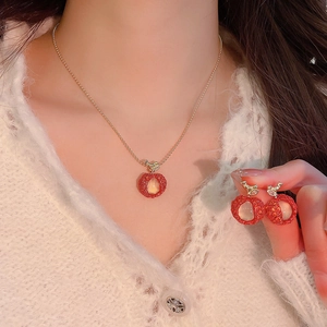 Close-up detail of a sweet red apple zircon resin necklace and earrings jewelry set.