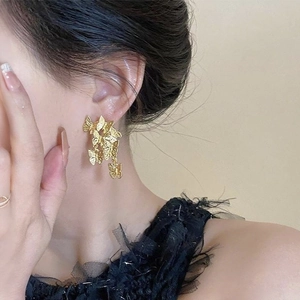 Macro shot of gold butterfly cluster earrings worn by a model with elegant black lace clothing