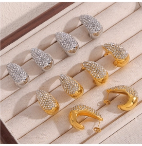 Gros plan de boucles d'oreilles en C dorées et argentées avec strass sur velours