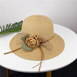 Primer plano del sombrero de paja caqui con flores de tela marrón claro y encaje de malla