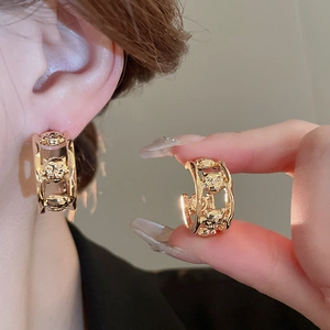 Macro detail of gold hoop earrings featuring three sculpted leopard heads and side profile