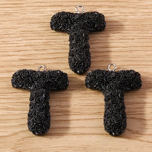 Detailed close-up of three black 3D T-letter charms with micro-rose texture for DIY jewelry