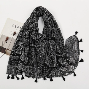 Detailed view of black and white paisley printed scarf with hand-knotted fringe edges