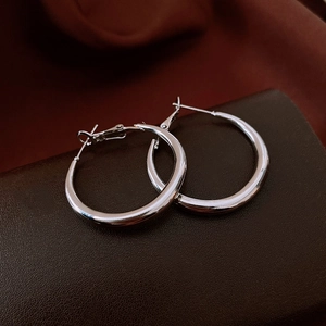 Detailed macro view of silver hoop earrings with polished mirror finish on dark leather