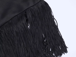 Detail view of smooth black satin fabric with dense long fringe trim for formal dress