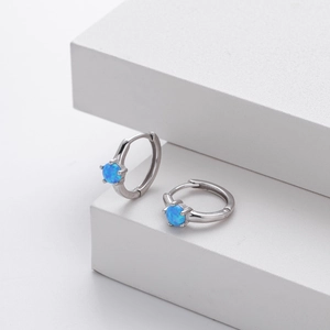 Detail of silver S925 earrings with blue opal inlays on a white stone background