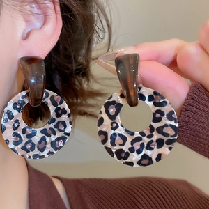 Close-up of model wearing leopard print acrylic hoop earrings with a brown knit sweater