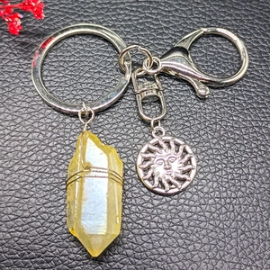 Natural yellow crystal pendant keychain with silver sun face charm on black background