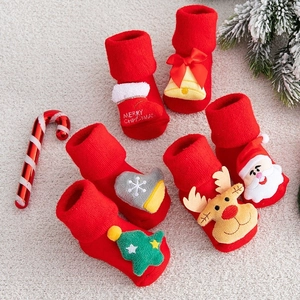 Close-up of festive red baby Christmas socks with 3D Santa and reindeer plush ornaments